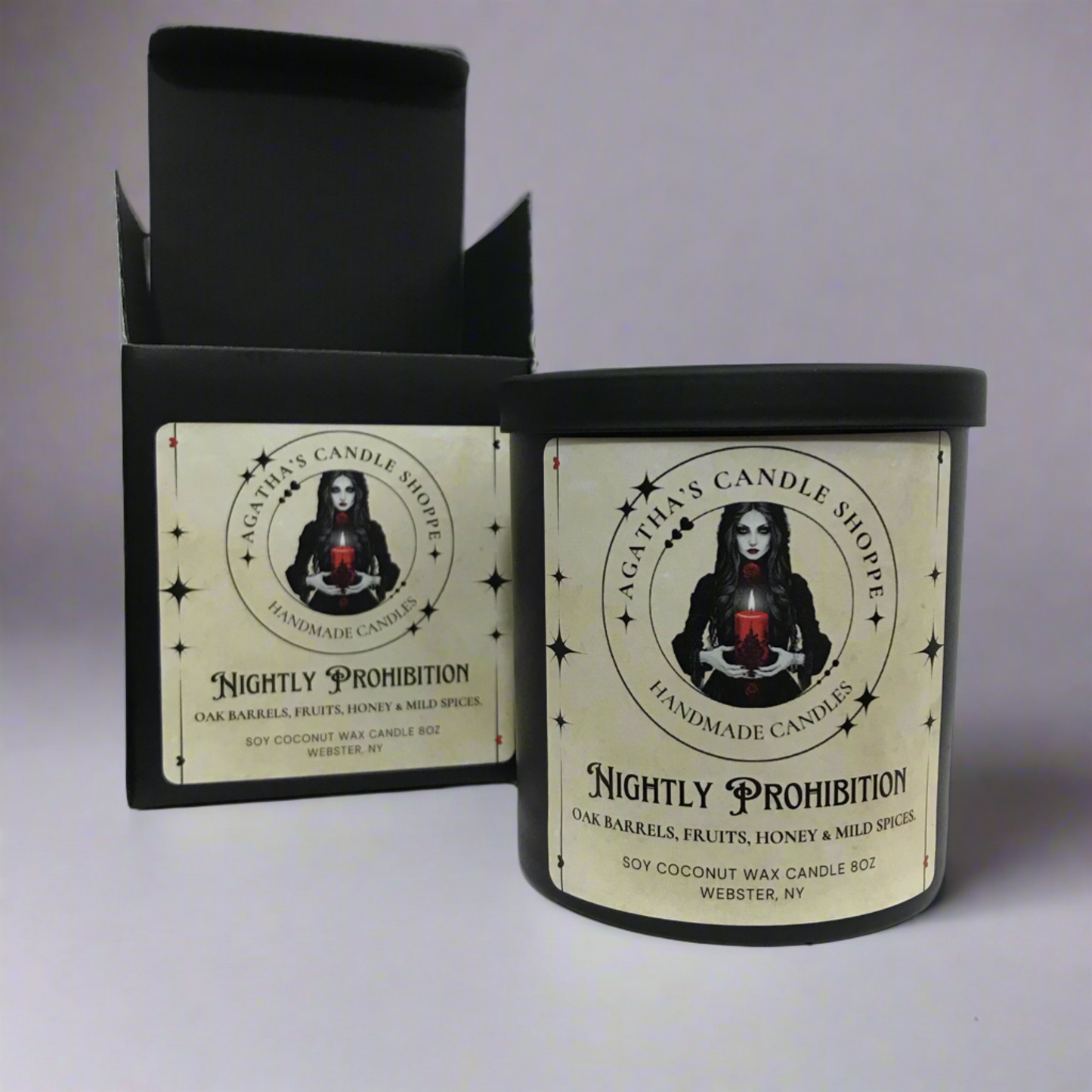 Candle box of 'Agatha's Candle Shoppe' label as Nightly prohibition, scent of oak, fruit, honey and spice, with a gothic, witchy theme against studio grey backdrop with dim lights