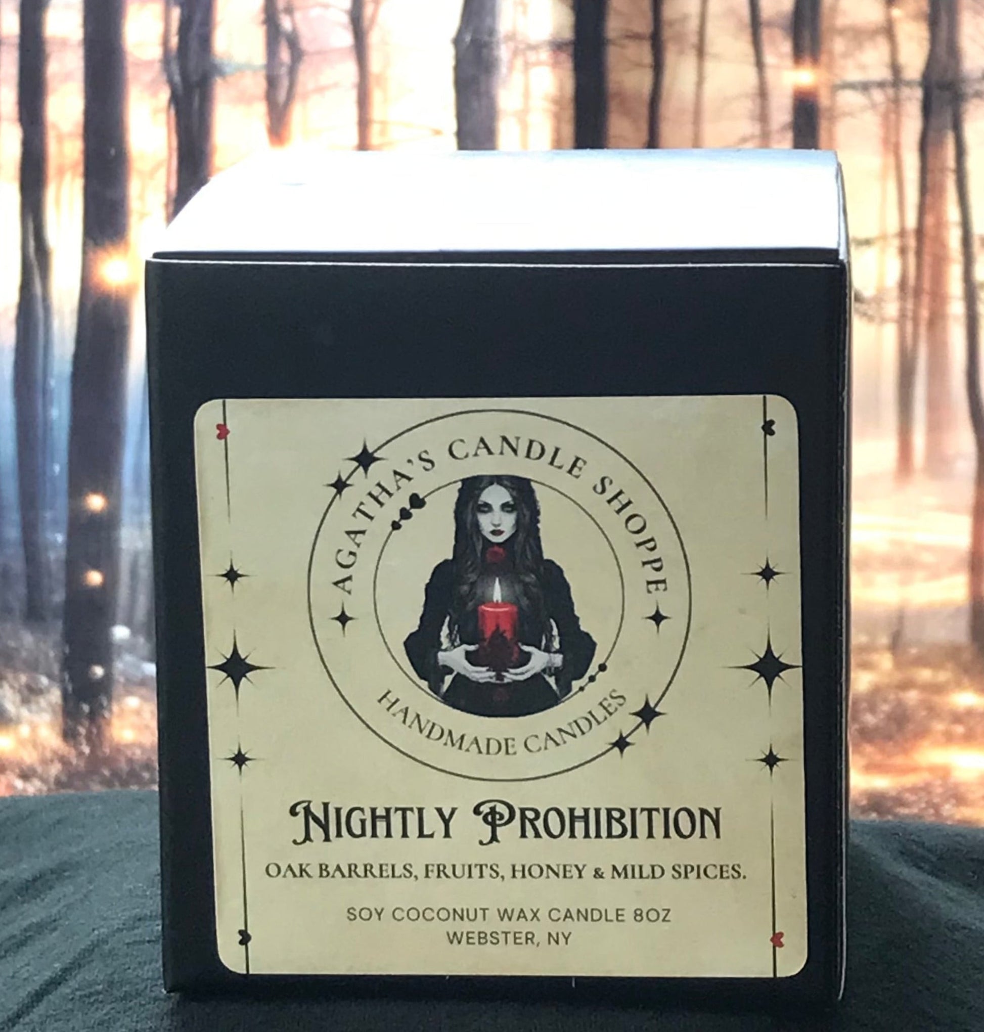 Candle box of 'Agatha's Candle Shoppe' label  as Nightly prohibition, scent of oak, fruit, honey and spice, with a gothic, withy theme against a forest background with mystical twinkle lights
